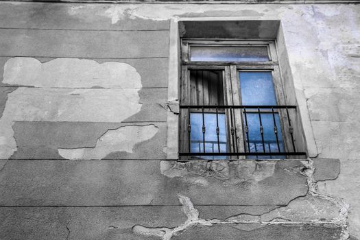 Old house facade with wooden damaged window in Novelda village, Valencia community, Spain.