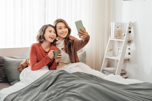 two girls taking a selfie while having lazy weekend at home