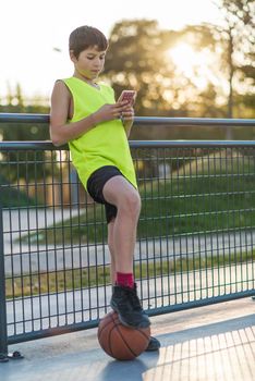 A Young male using a phone outdoors at sunset