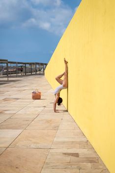 A Woman doing a handstand wearing swimwear