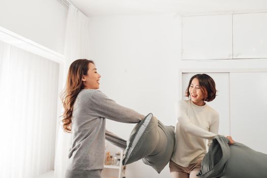 Asian woman with attractive smile while play pillow with friend.