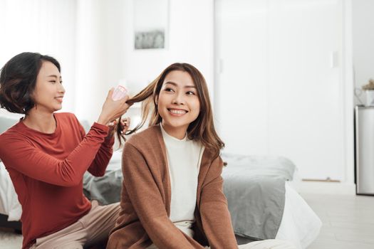 Young beautiful Asian couple love friend woman do hair on bed in bedroom.