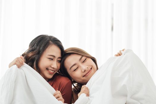 Smiling Two Asian young lovely couple sitting on white bed and happy.