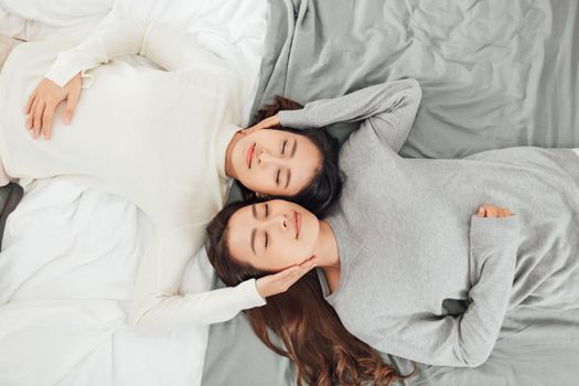 Overhead close up of young couple lesbian lying in bed together.