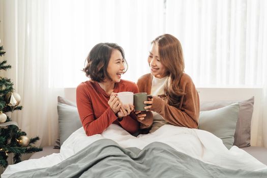 friendship concept - two beautiful women drinking coffee or tea at home