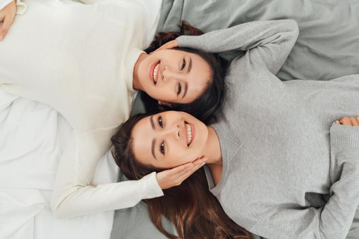 Two smiling women lie on bed