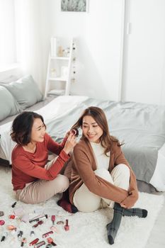 Young beautiful Asian couple love friend woman do hair on bed in bedroom.