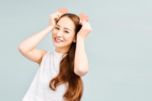 Happy asian woman holds two signs hearts in hands and smiles