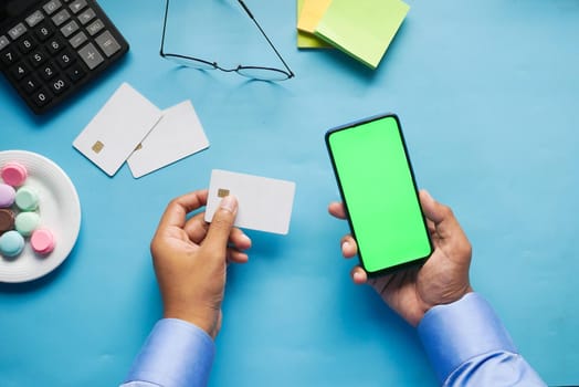 Man hand holding credit card and using smart phone shopping online .