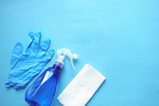 cleaning paper, bottle and hand gloves on blue .