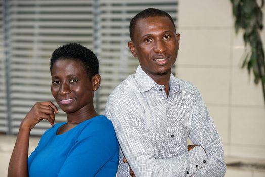 young couple standing staring at camera smiling.