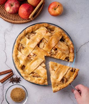 Autumn foods. Top view of homemade apple pie on white wooden table, hand taking a piece of pie