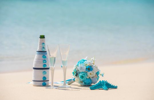 Closeup of champagne wedding romantic decorations still life on tropical island sandy beach paradise with ocean in background