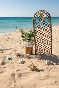 Closeup of wedding sign and decorations on tropical island sandy beach paradise with ocean in background