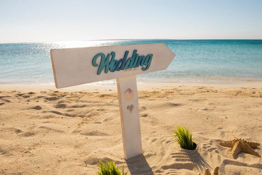 Closeup of wedding sign on tropical island sandy beach paradise with ocean in background