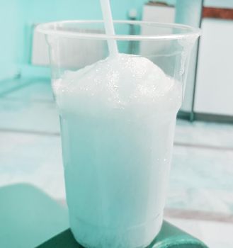 Transparent glass with foam and oxygen cocktail with a straw, blue tinted.