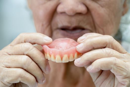 Asian senior or elderly old woman patient holding to use denture in nursing hospital ward, healthy strong medical concept