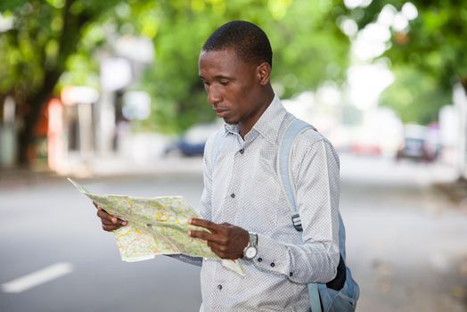 young tourist man looking for his landmarks with a map in the city. Tourism concept. Outside.
