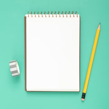 desk arrangement with empty notepad blue background. Beautiful photo