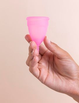 close up hand holding pink menstrual cup. High resolution photo