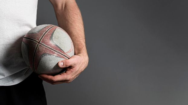 front view male rugby player holding ball hip with copy space. Beautiful photo