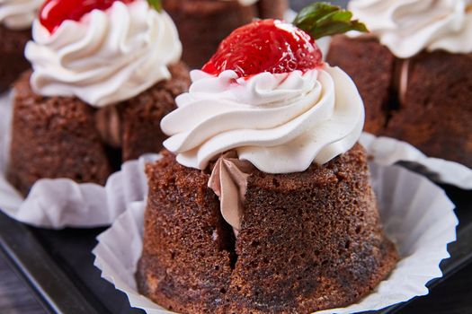 Image of Detail of delicious bakery cupcake filled with frosting and topped with cherry