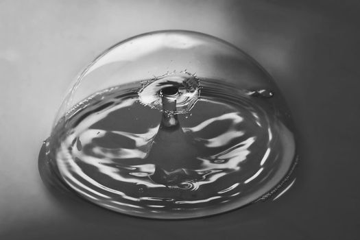 Image of Black and white of pristine bubble containing ripples from two water drops colliding in air