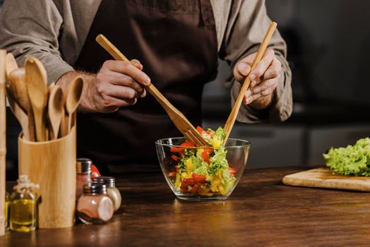 mid shot chef mixing salad ingredients. High resolution photo