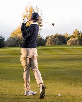 back view man playing grassy golf field. High resolution photo