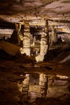 Image of Majestic pair of stalagmites reflecting in crystal clear water of deep cave