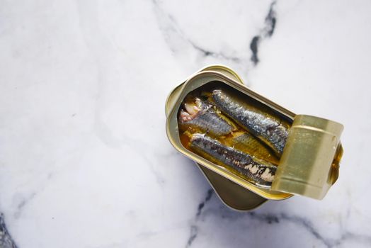 open tin of sardines on white tiles background