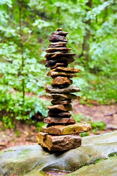 Image of Cairn stack of small stones against bright green woods