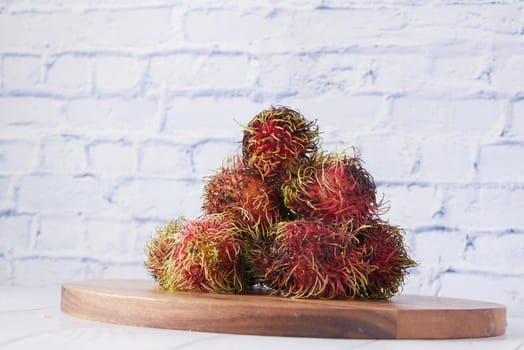 stack of rambutan in a chopping board on table .
