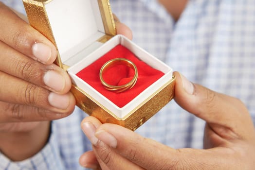 young man hold a wedding ring in a box .