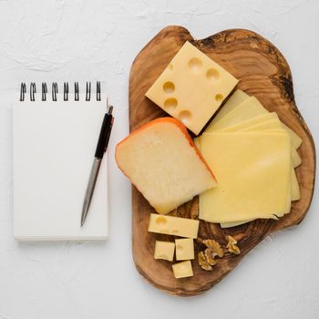 delicious cheese platter blank spiral dairy with pen against plain background. Beautiful photo