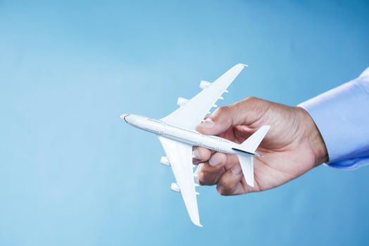 Hand holding toy plane over blue background ,