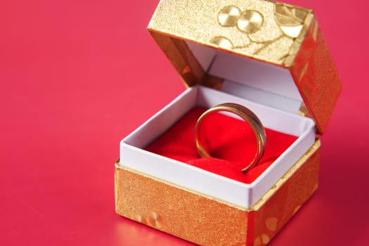 wedding ring in a box on red background