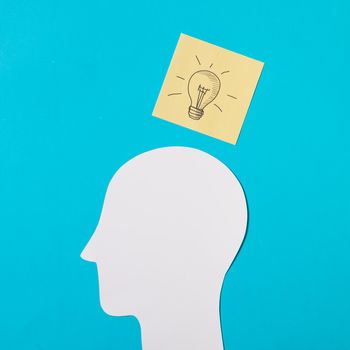drawn light bulb icon sticky note paper cut out head against blue background. Resolution and high quality beautiful photo