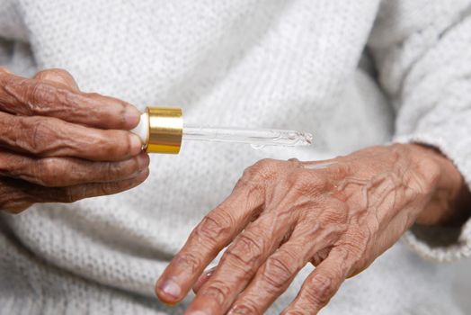 senior women applying essential oils on hand ,