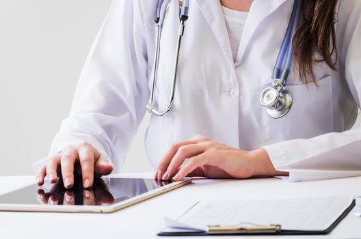 close up female doctor using digital tablet medical report desk. High resolution photo