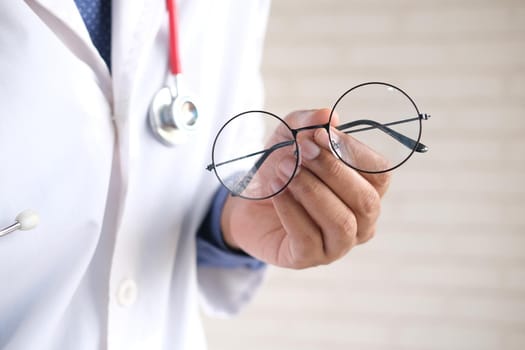 doctor hands giving pair of black glasses to patient