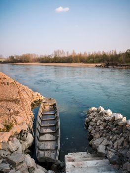 A boat moored to a stone shore. An old wooden boat moored to a stone shore and a small stone cove on the river Drava. Croatia.