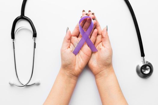 crop hands with violet ribbon near stethoscope. High resolution photo