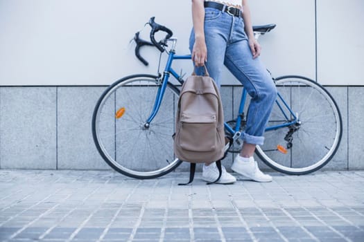 low section young woman standing near bicycle holding backpack. Beautiful photo