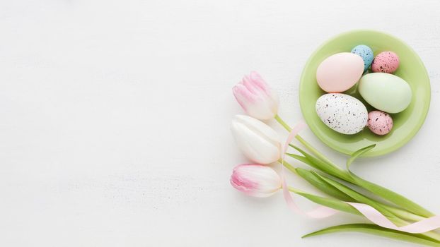 top view colorful easter eggs plate with tulips. High resolution photo