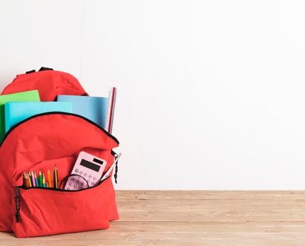 red school bag with essential supplies. High resolution photo