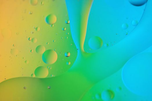 Colorful abstract background with oil drops on water. Yellow green blue color