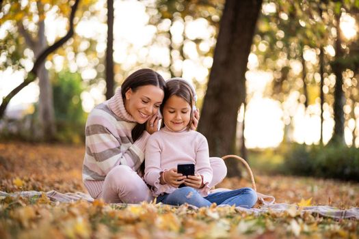 Mother and daughter enjoying autumn in park.