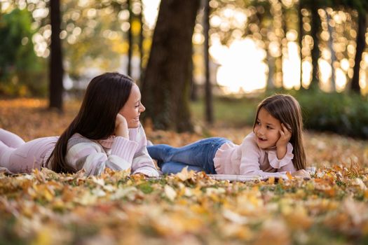 Mother and daughter enjoying autumn in park.