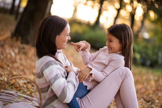 Mother and daughter enjoying autumn in park.